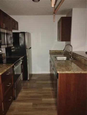 a kitchen with granite countertop a sink stove and refrigerator