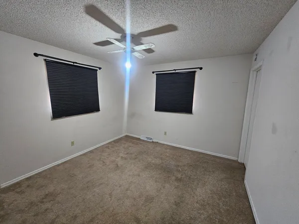 an empty room with a flat screen tv and a ceiling fan