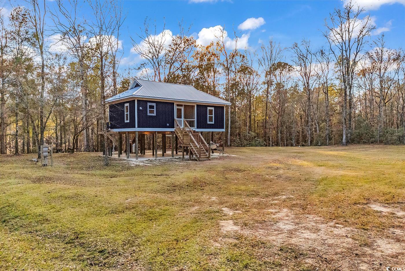 32 Old Place Kingstree, SC 29556 - Photo 30 of 40 View of front of home with a front yard, a metal roof, stairs, a forest view, and a patio area