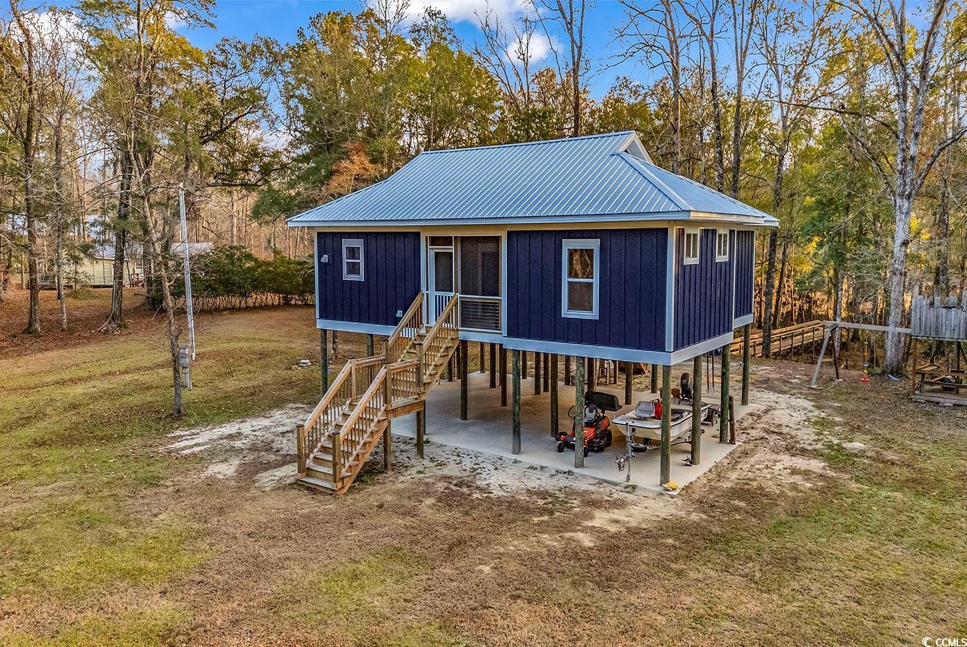 32 Old Place Kingstree, SC 29556 - Photo 32 of 40 Rear view of property featuring stairs, a carport, a metal roof, a lawn, and a patio area