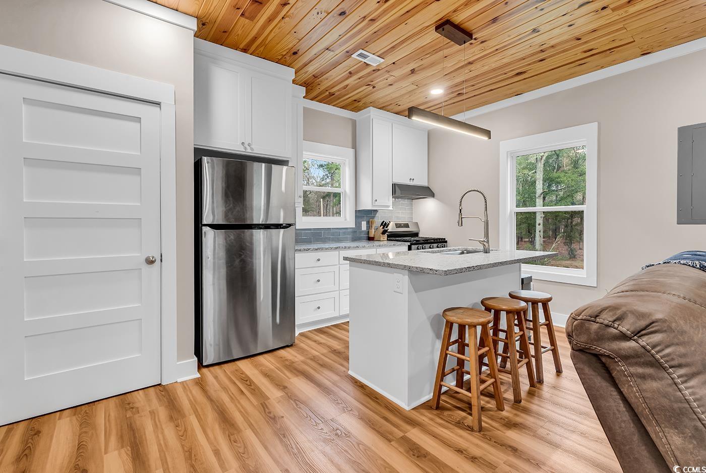 32 Old Place Kingstree, SC 29556 - Photo 5 of 40 Kitchen featuring appliances with stainless steel finishes, wood ceiling, a kitchen breakfast bar, a kitchen island with sink, and light stone countertops