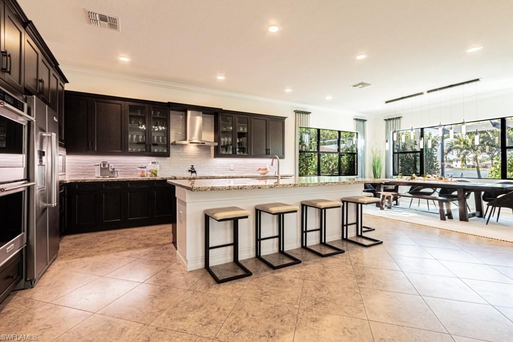 9380 Glenforest Drive Naples, FL 34120 - Photo 16 of 49 a large dining hall with stainless steel appliances kitchen island granite countertop a large counter top a sink and cabinets