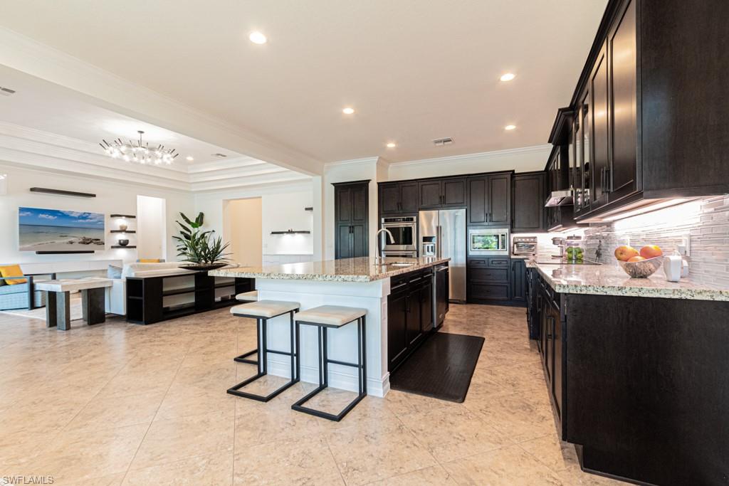 9380 Glenforest Drive Naples, FL 34120 - Photo 18 of 49 a kitchen with stainless steel appliances kitchen island granite countertop a table chairs sink and cabinets