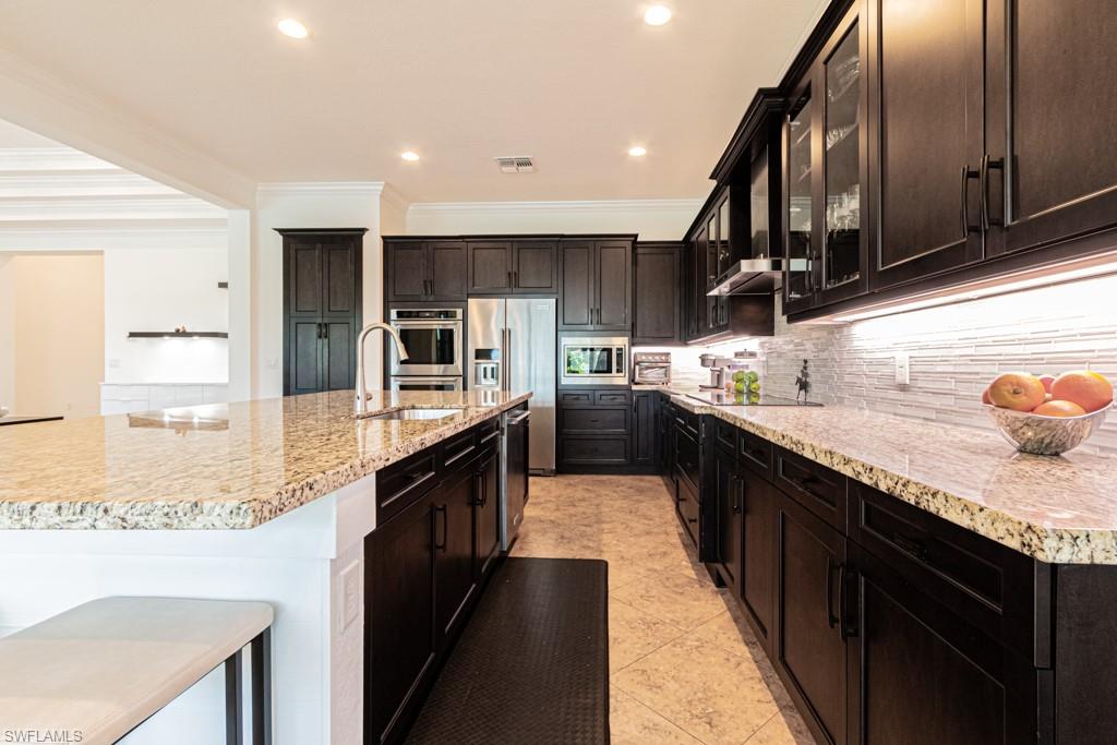 9380 Glenforest Drive Naples, FL 34120 - Photo 19 of 49 a large kitchen with stainless steel appliances wooden cabinets a stove and a center island