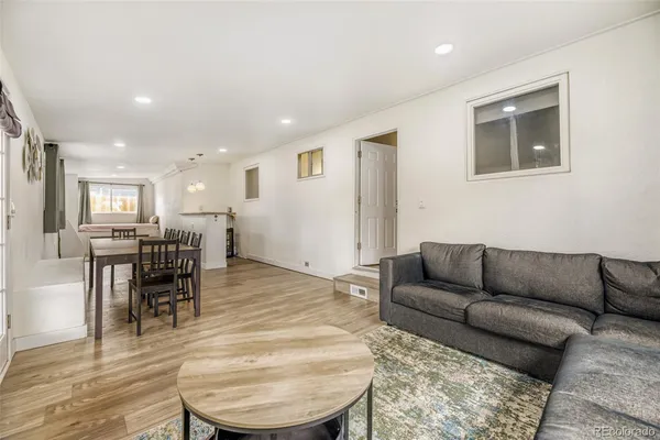 a living room with furniture and a dining table with wooden floor