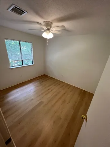 an empty room with windows and chandelier fan