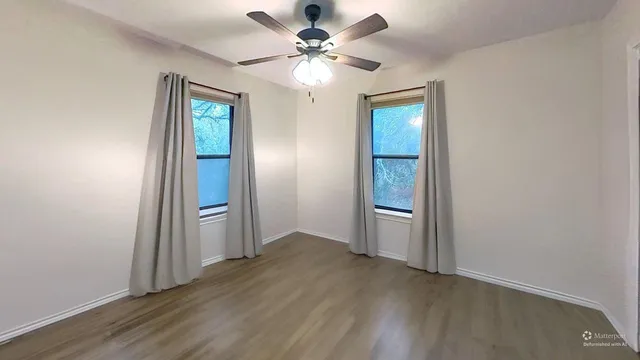 an empty room with wooden floor closet and windows