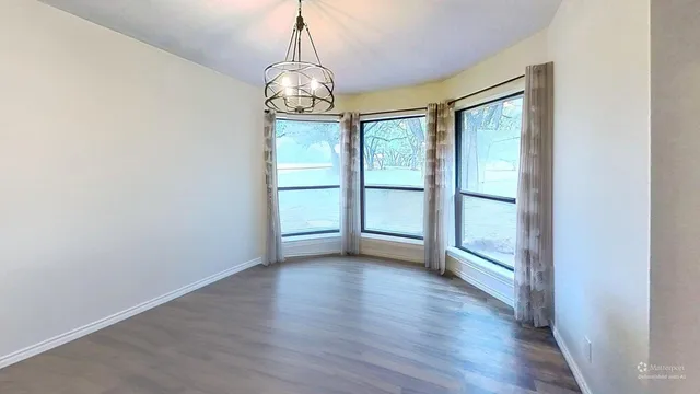 a view of an empty room with wooden floor and fan