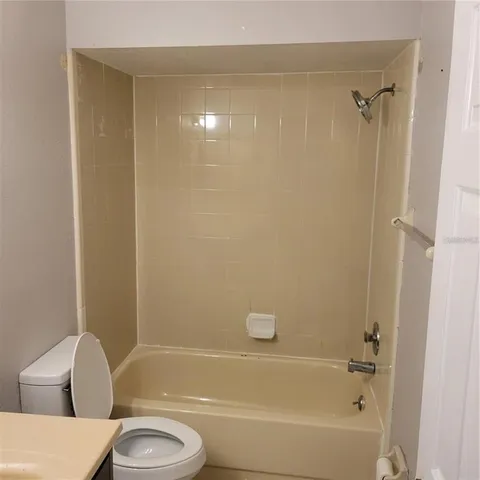 a bathroom with a granite countertop bathtub shower sink vanity and toilet