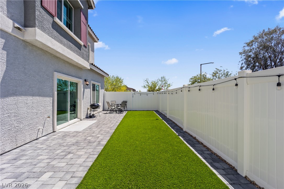 7204 North Decatur Boulevard, Unit 5 North Las Vegas, NV 89084 - Photo 21 of 34 An inviting backyard features a stone-paved patio alongside a low-maintenance artificial lawn.