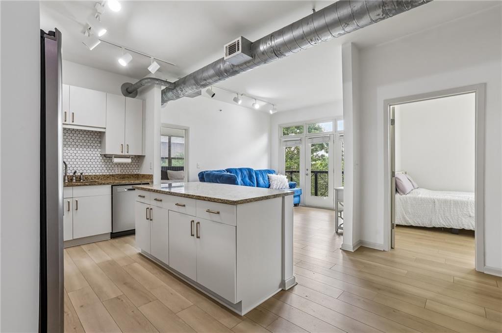 5300 Peachtree Road, Unit 3506 Atlanta, GA 30341 - Photo 1 of 25 a kitchen with granite countertop a refrigerator a stove a sink and white cabinets with wooden floor