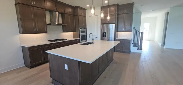 a kitchen with kitchen island a sink dishwasher a stove and a refrigerator with wooden floor