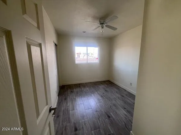 an empty room with wooden floor fan and window