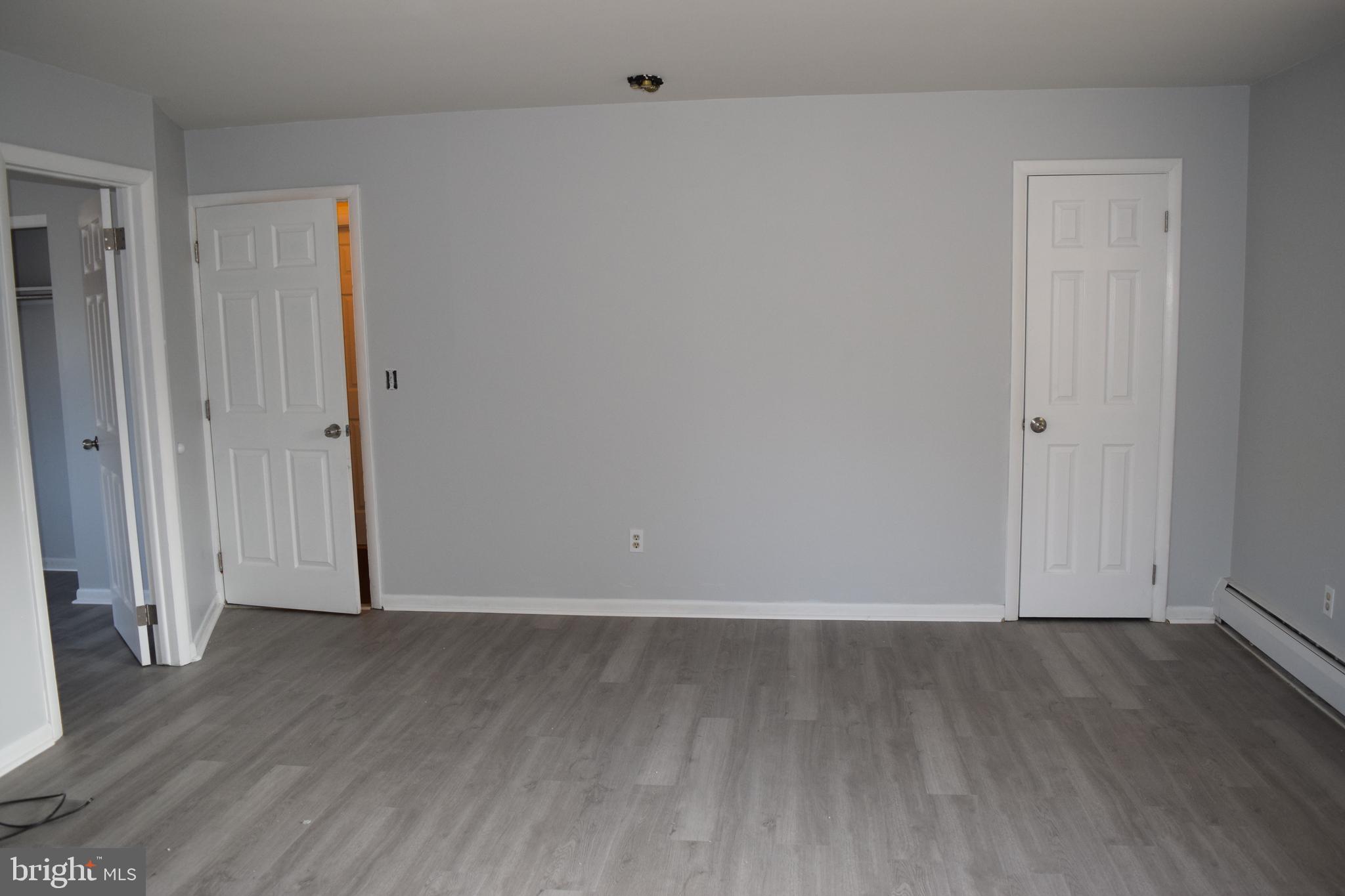a view of an empty room with wooden floor and closet