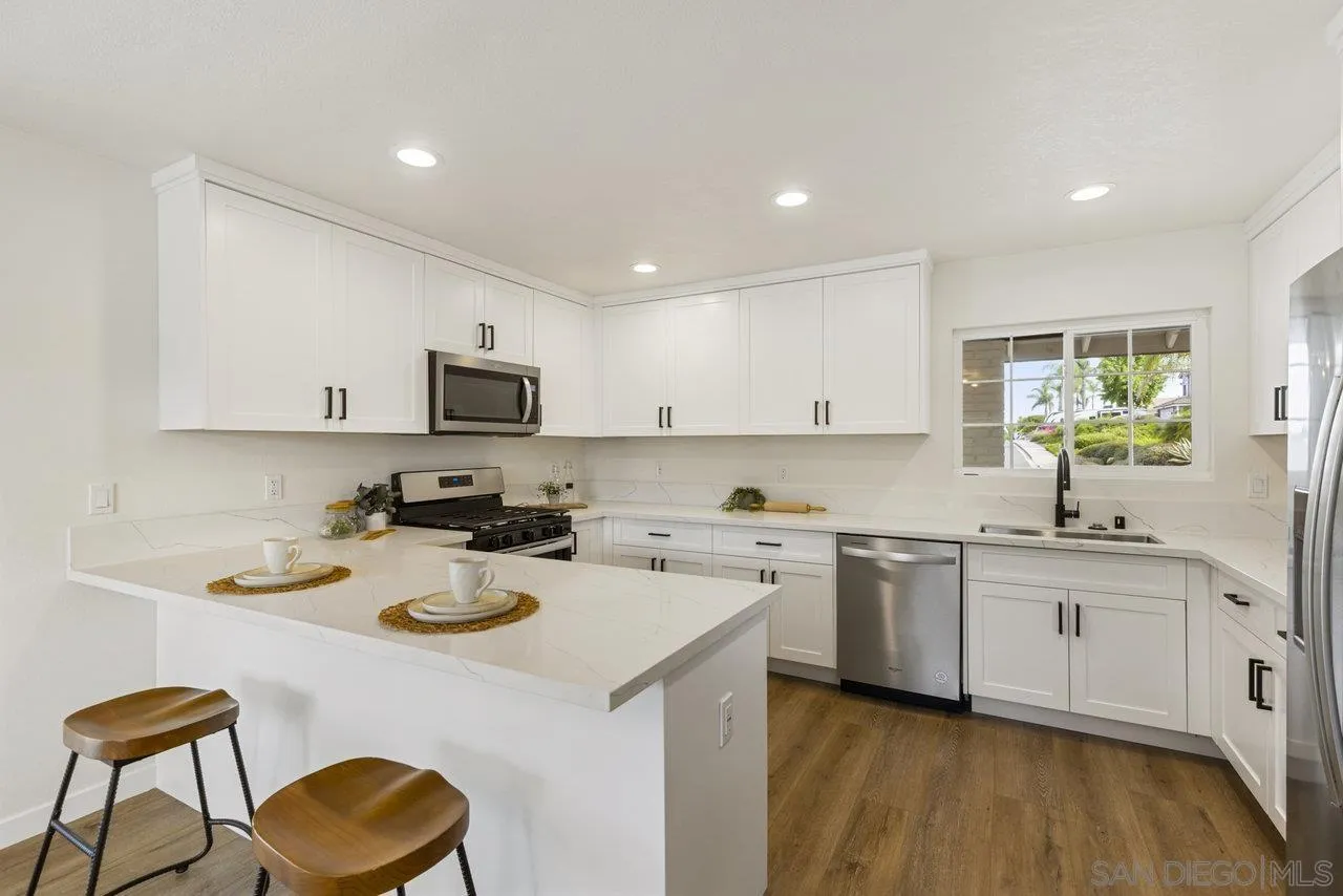 a kitchen with a sink a stove a refrigerator and white cabinets