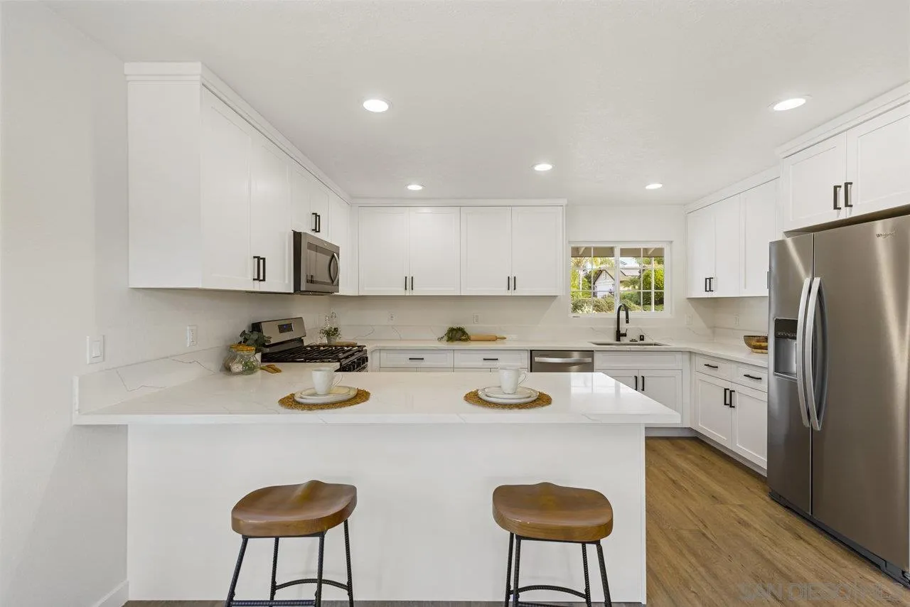 1066 Fulton Road San Marcos, CA 92069 - Photo 13 of 36 a kitchen with stainless steel appliances granite countertop a refrigerator a stove a sink dishwasher and white cabinets with wooden floor