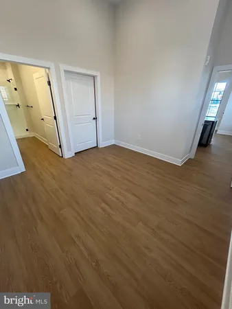 a view of an empty room with wooden floor and a mirror