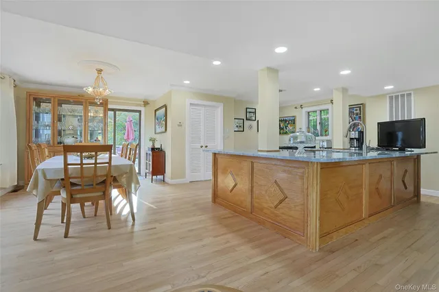 a living room with stainless steel appliances kitchen island granite countertop wooden floors and white cabinets