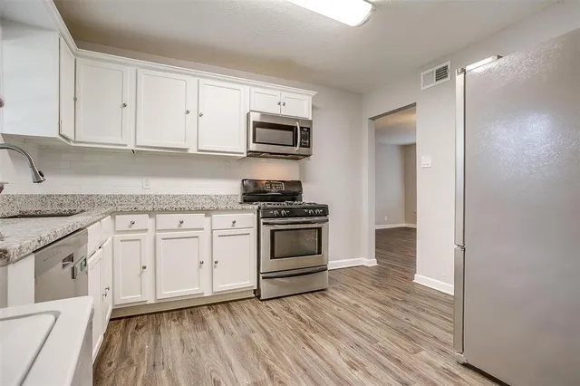 a kitchen with stainless steel appliances granite countertop a stove and white cabinets