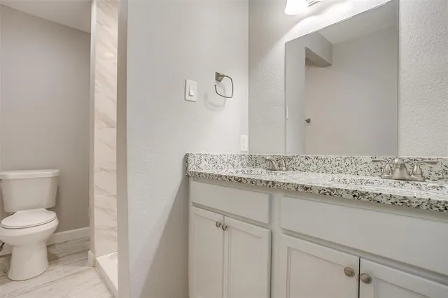 a bathroom with a granite countertop sink and a toilet