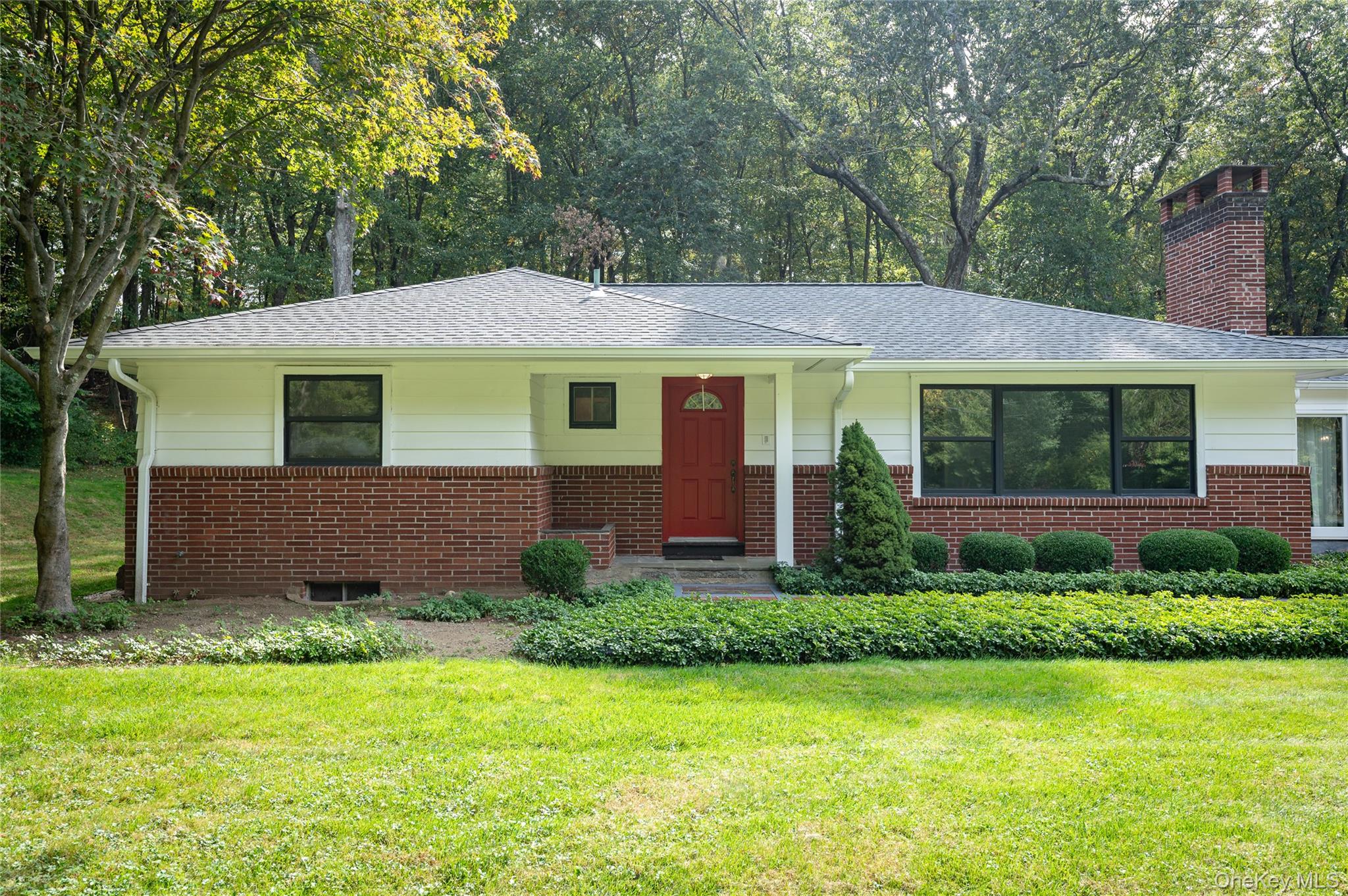 a view of a house with a yard plants and large tree