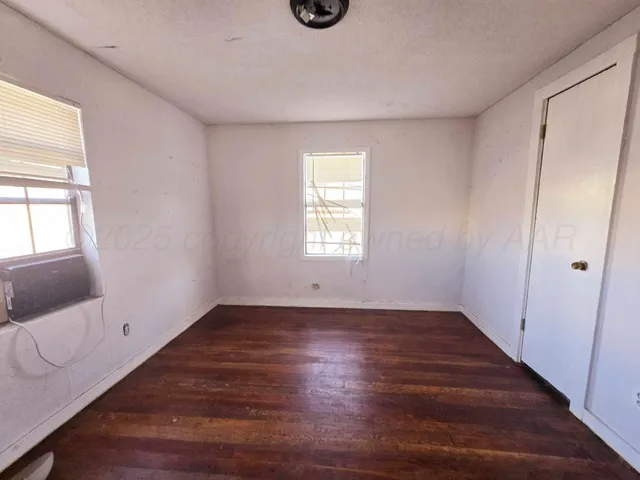 a view of an empty room with wooden floor and window