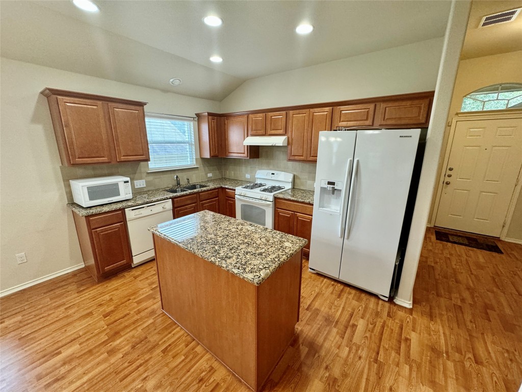 2209 Christoff Loop Austin, TX 78748 - Photo 6 of 25 a kitchen with stainless steel appliances granite countertop a refrigerator a stove top oven a sink dishwasher and wooden floor