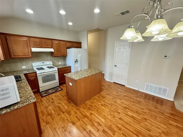 a kitchen with stainless steel appliances granite countertop a sink a stove cabinets and wooden floor