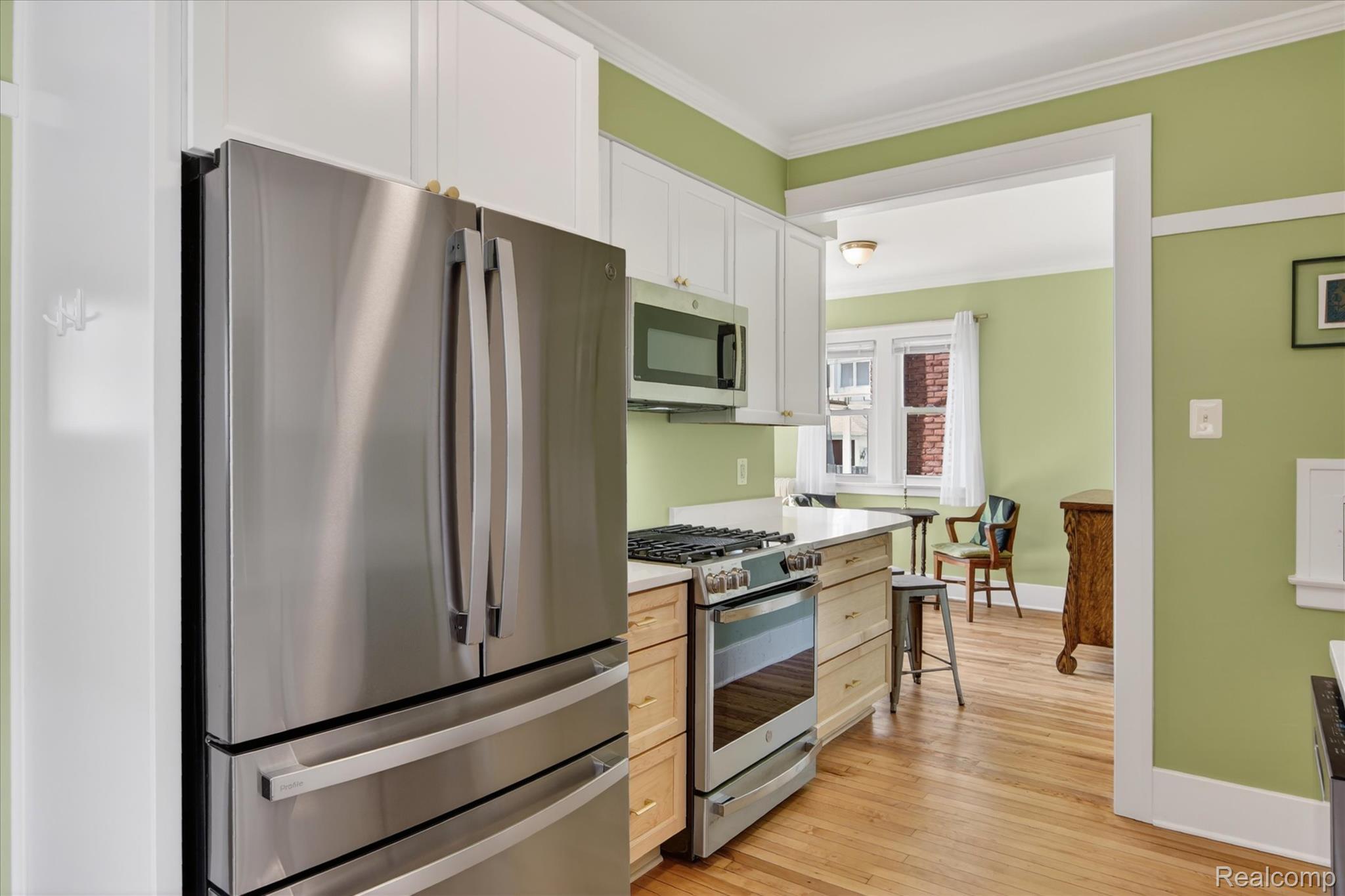 925 Nottingham Road Grosse Pointe, MI 48230 - Photo 1 of 46 Kitchen with stainless steel appliances, light wood-style flooring, ornamental molding, and white cabinetry