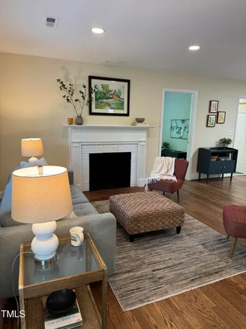 a living room with table chairs and a wooden floor