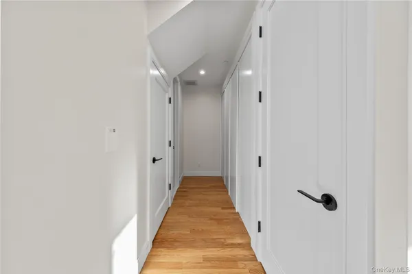 a view of a hallway with wooden floor and a bathroom