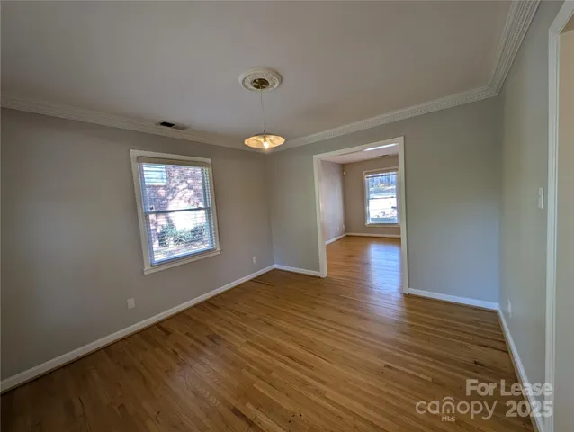 a view of empty room with window and wooden floor