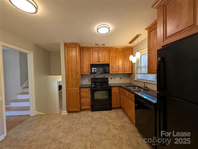 a kitchen with granite countertop a refrigerator and a stove top oven