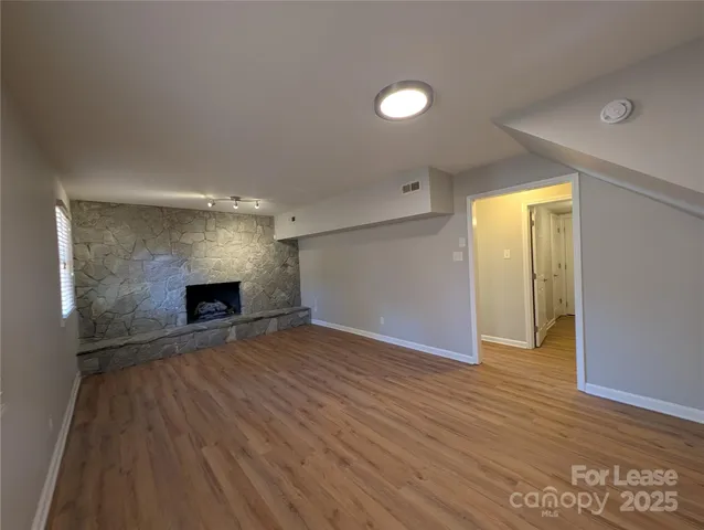 a view of empty room with wooden floor and fireplace