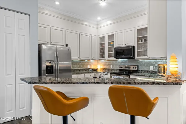 a kitchen with stainless steel appliances granite countertop a sink dishwasher and white cabinets with wooden floor