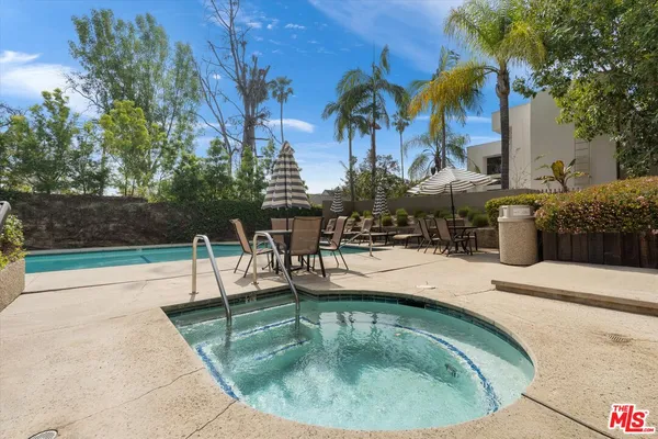 a view of a house with potted plants and a large tree