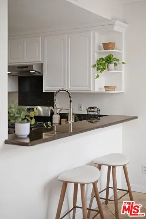 a kitchen with a sink a stove and white cabinets