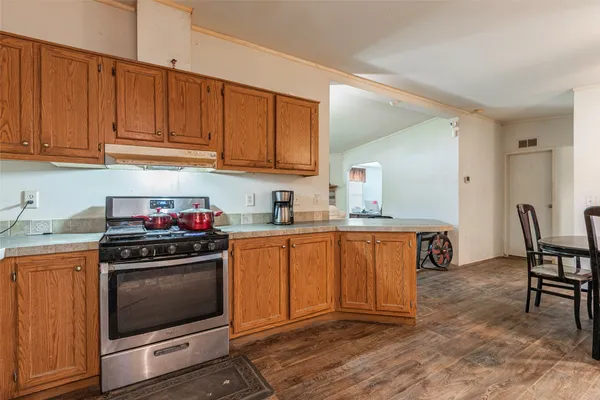 a kitchen with stainless steel appliances granite countertop a stove top oven a sink dishwasher and cabinets with wooden floor