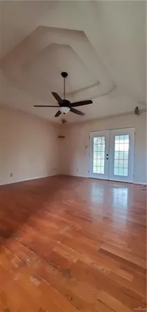 an empty room with wooden floor fan and windows