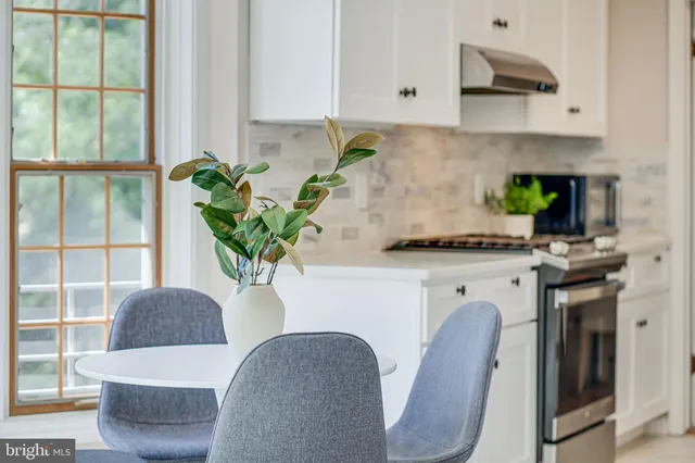 a view of a dining room and livingroom with furniture a floor to ceiling window and a view of kitchen