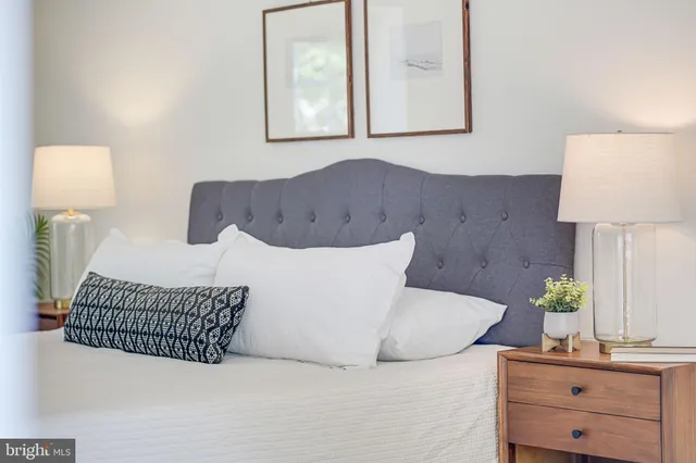 a spacious bedroom with a bed a chandelier and windows