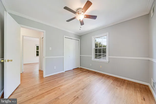 a view of empty room with wooden floor and fan