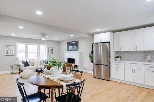 a kitchen with stainless steel appliances granite countertop a refrigerator a sink dishwasher a dining table and chairs with wooden floor