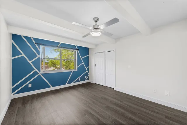 an empty room with wooden floor fan and windows