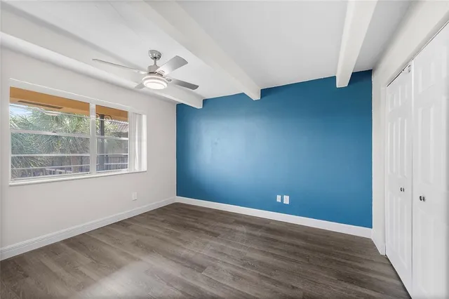a view of empty room with wooden floor and fan