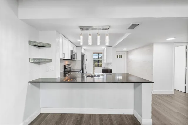 a kitchen with kitchen island granite countertop a refrigerator and a sink