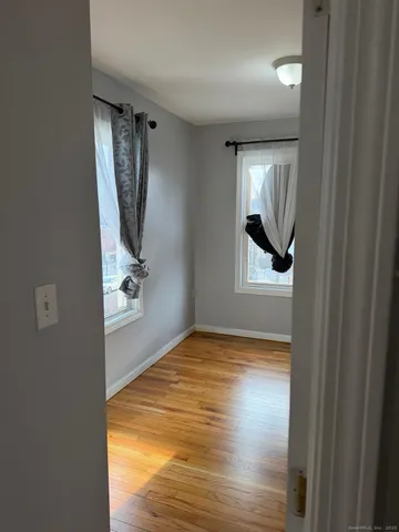 a view of empty room with window and wooden floor