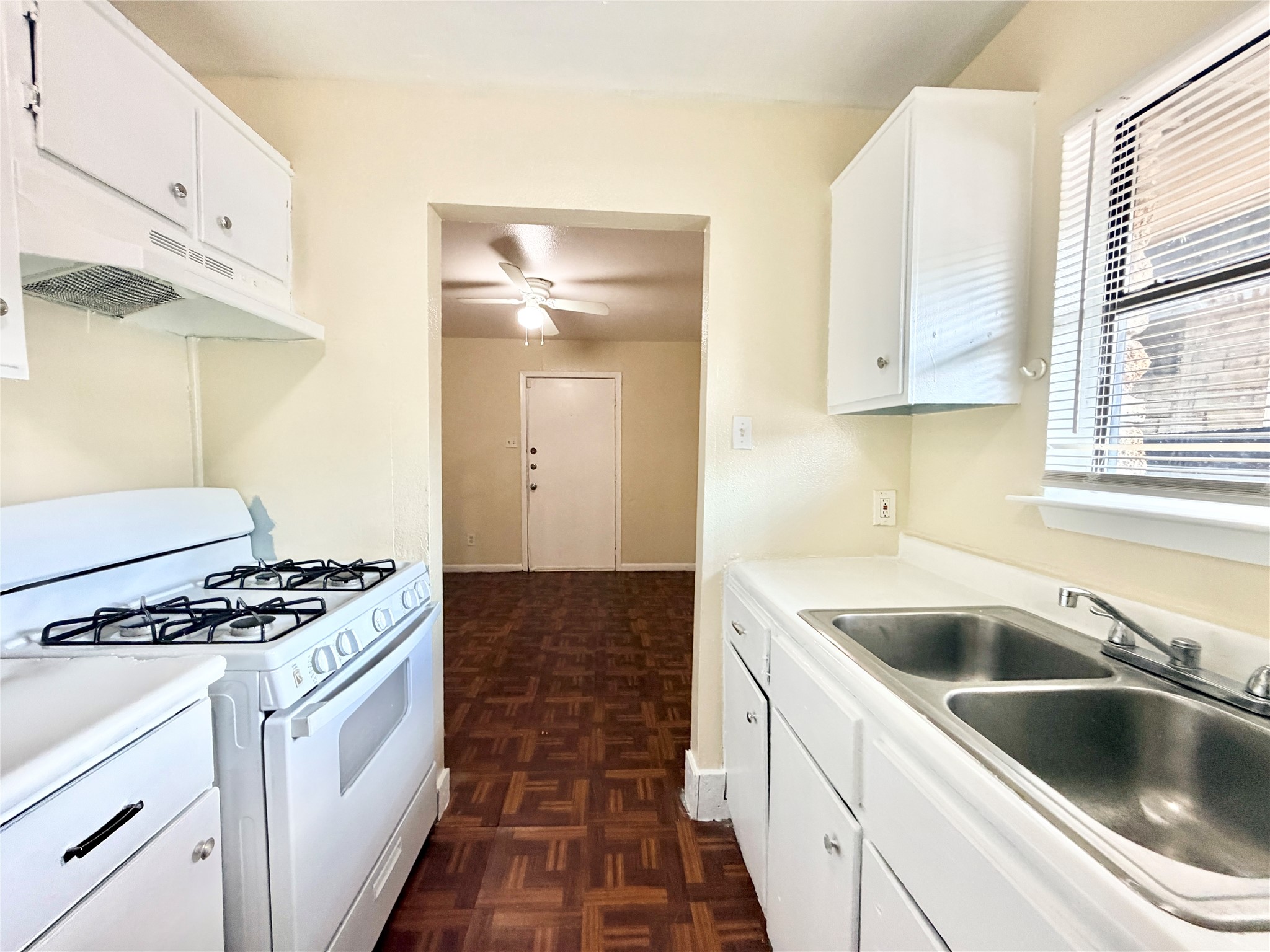 6257 Manor Road, Unit B Austin, TX 78723 - Photo 10 of 38 Kitchen featuring white cabinetry, a dual basin stainless steel sink, a gas range, and a window with blinds