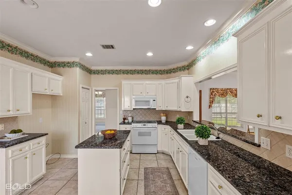 a kitchen with stainless steel appliances granite countertop a stove a sink and white cabinets