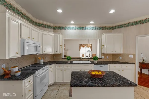a kitchen with granite countertop a sink a stove and cabinets